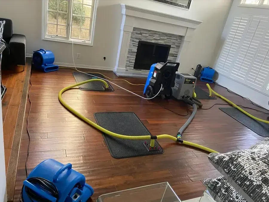 Hardwood floor drying mats, air movers and a dehumidifier in a Spring Hill living room